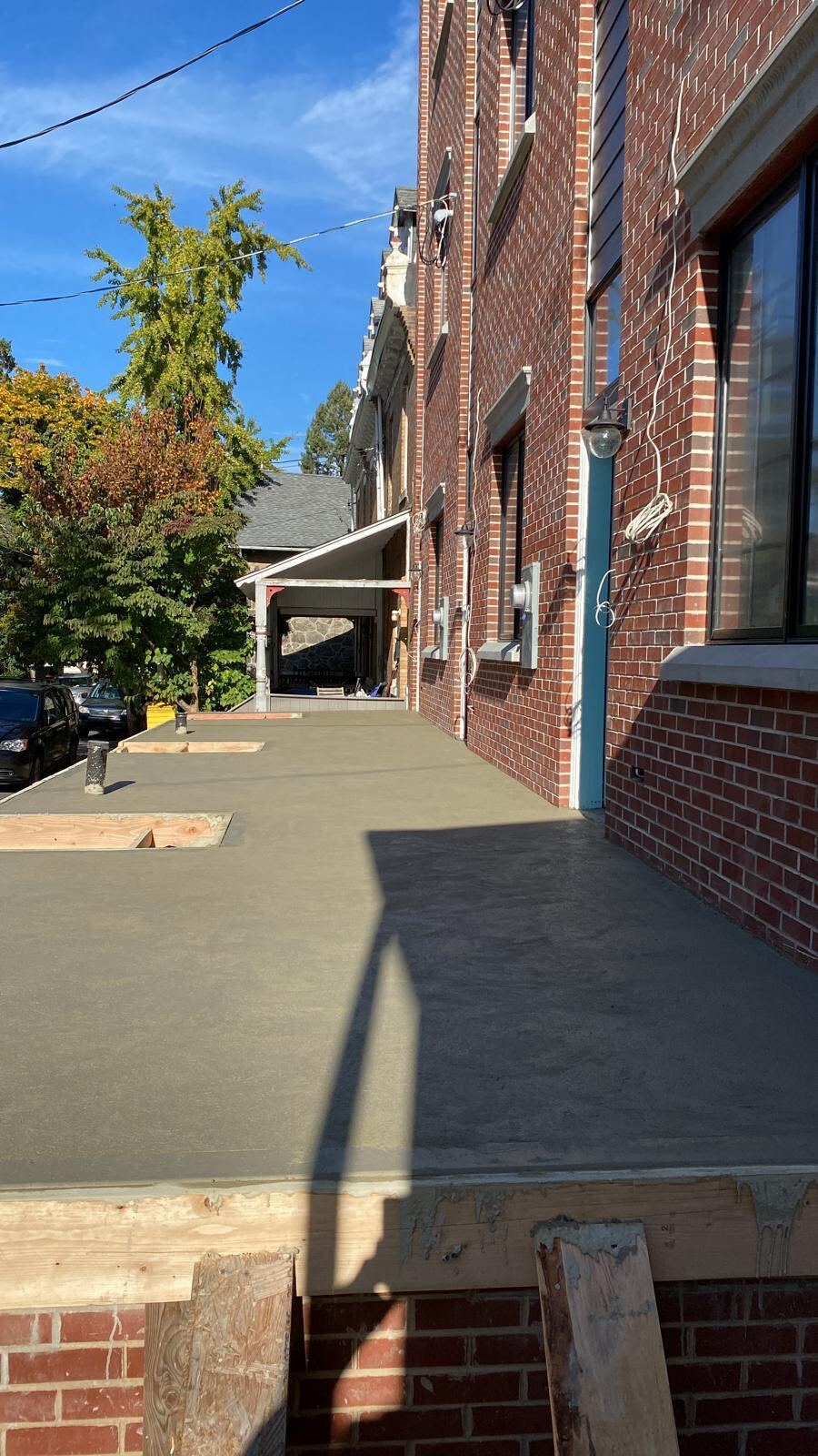 Freshly poured concrete walkway alongside a brick building completed by Affinity Contractors
