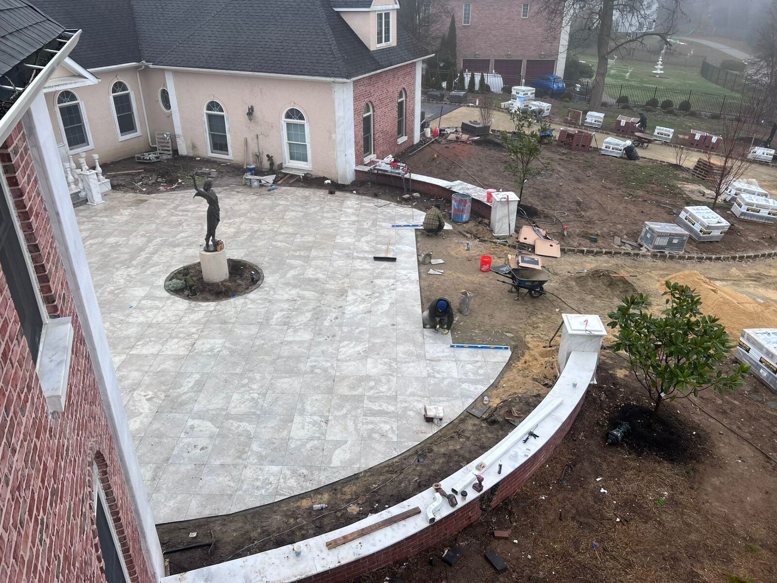 Large marble tile patio installation with curved retaining wall at a Bucks County estate by Affinity Contractors