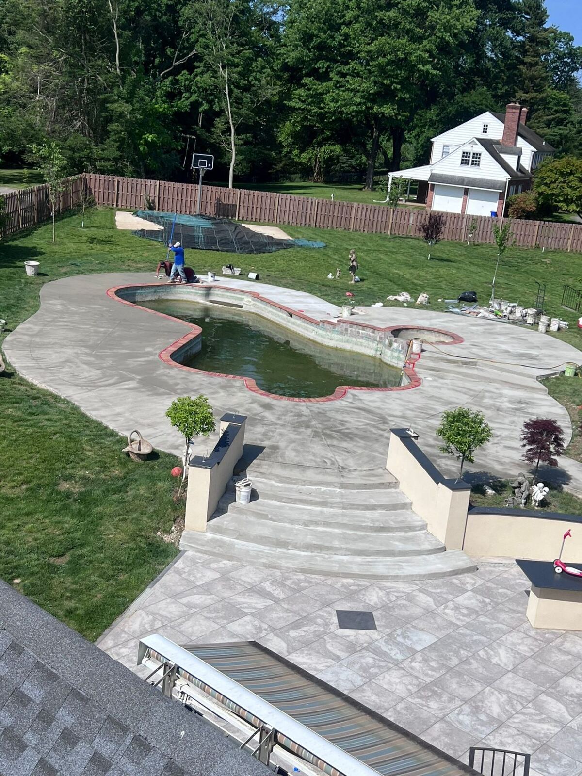 Custom freeform inground pool with brick coping and stamped concrete pool deck installed by Affinity Contractors in Montgomery County PA