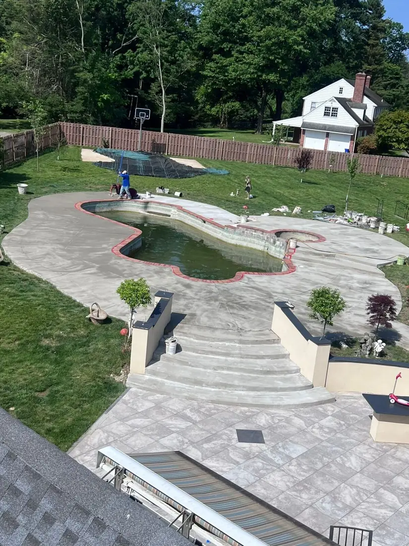 Custom freeform inground pool with brick coping and stamped concrete pool deck installed by Affinity Contractors in Montgomery County PA