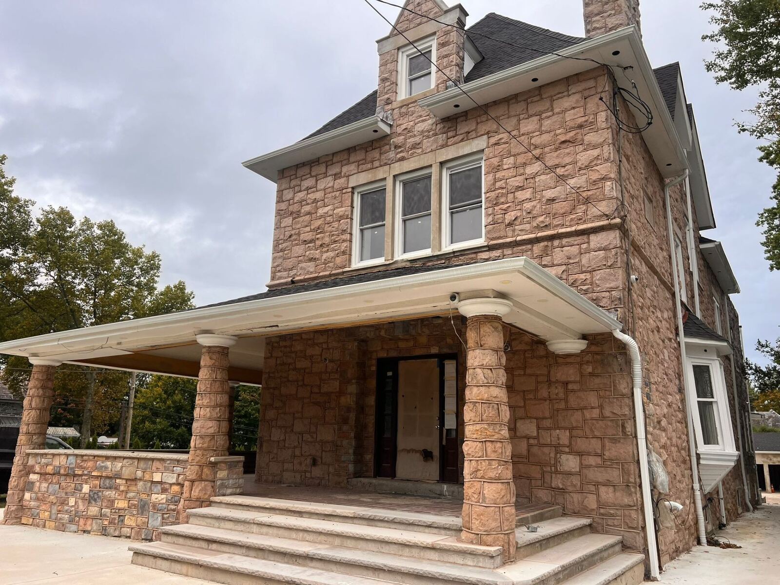 Restored stone Victorian home exterior with rebuilt porch and columns by Affinity Contractors in Philadelphia